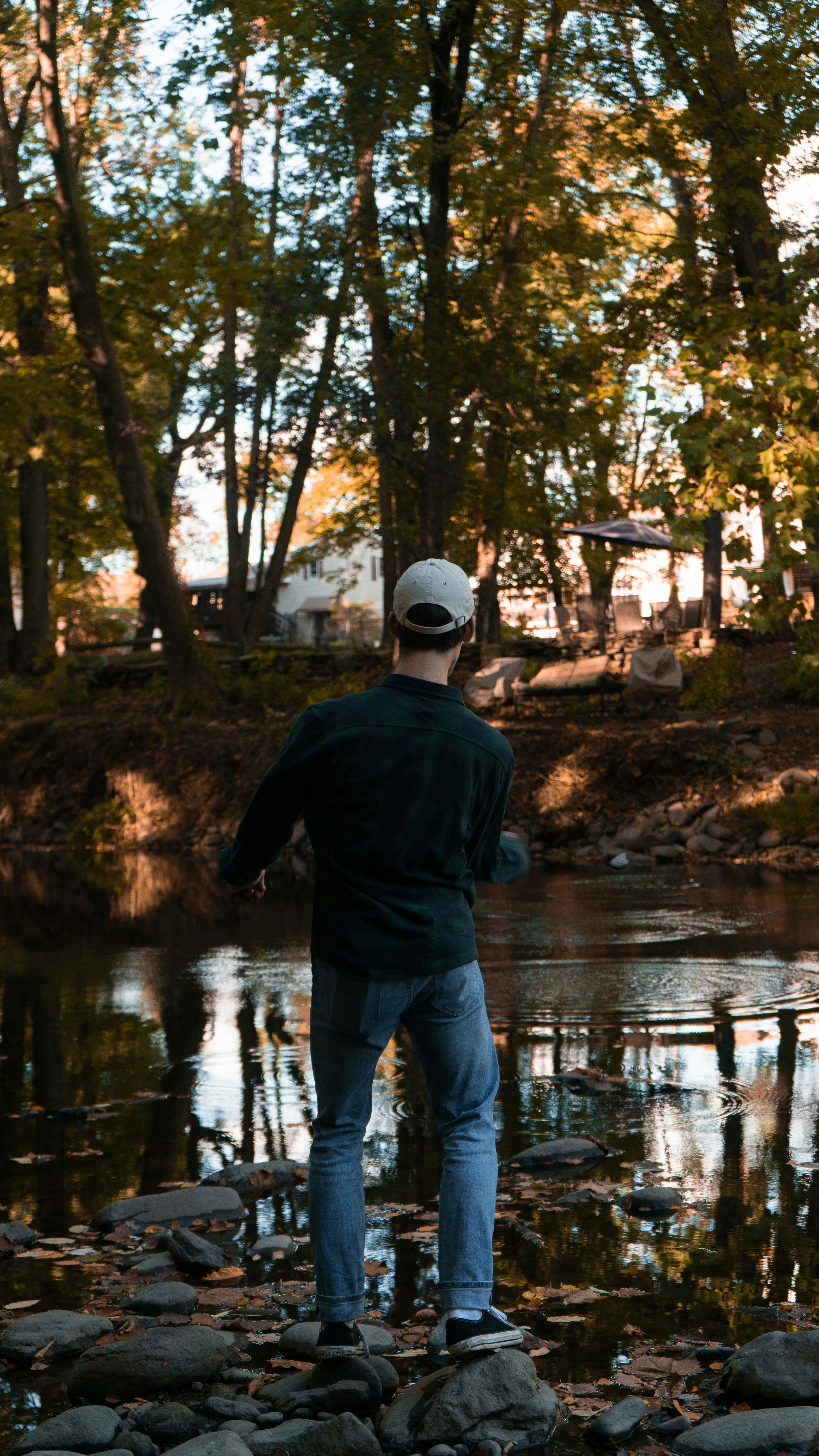 man in black jacket and blue denim jeans standing on river during daytime